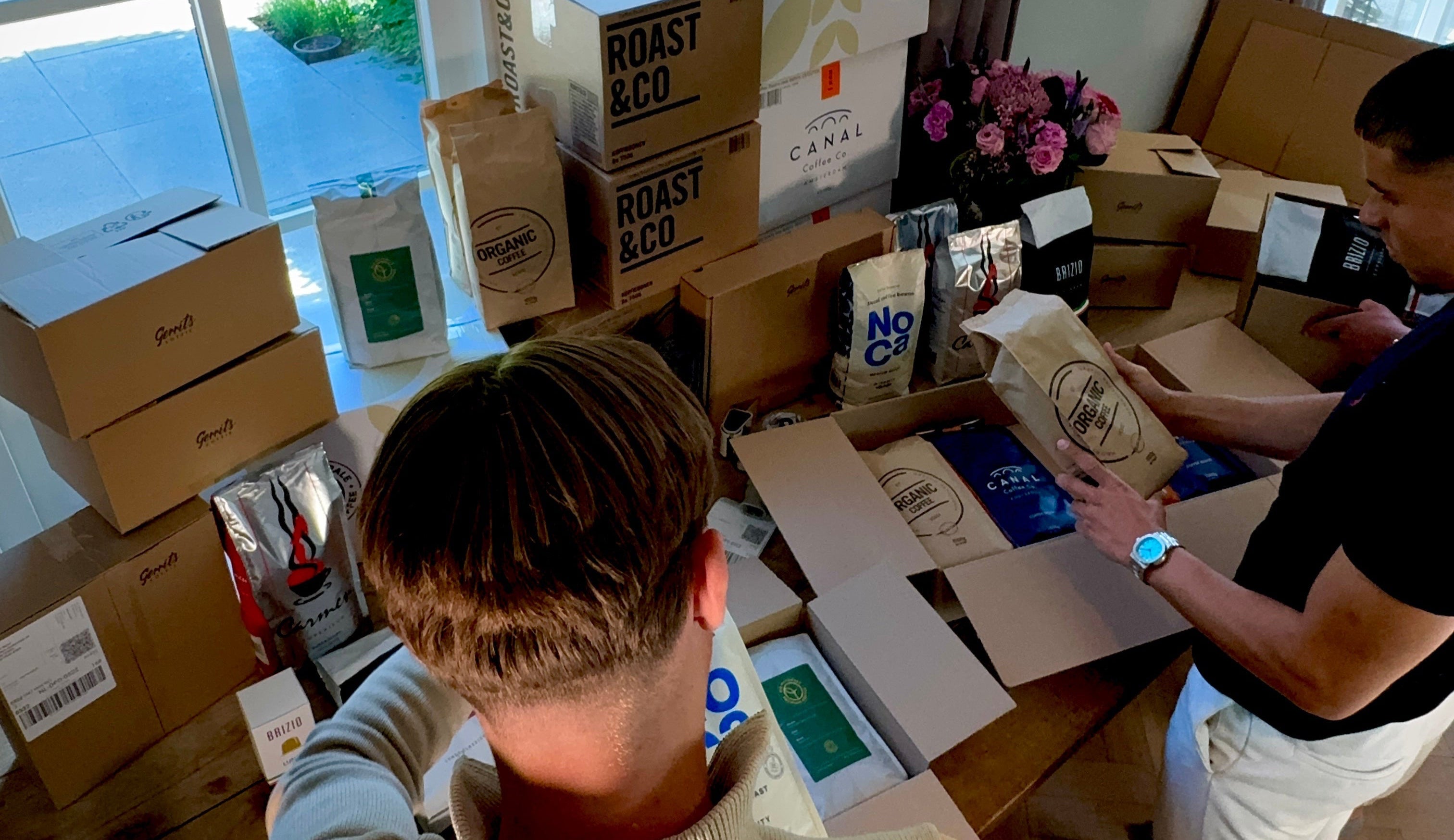 Twee medewerkers verpakken GerritsKoffie bestellingen met dozen en zakken koffie van Roast & Co, Canal en NoCa