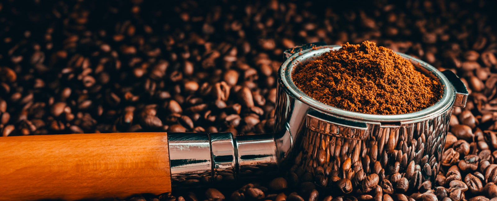 Portafilter gevuld met versgemalen GerritsKoffie, omringd door een zee van rijke, gebrande koffiebonen.